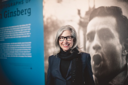 Lori Starr stands in front of a wall display for the current exhibit “Beat Memories: The Photographs of Allen Ginsberg.” photo/gary sexton